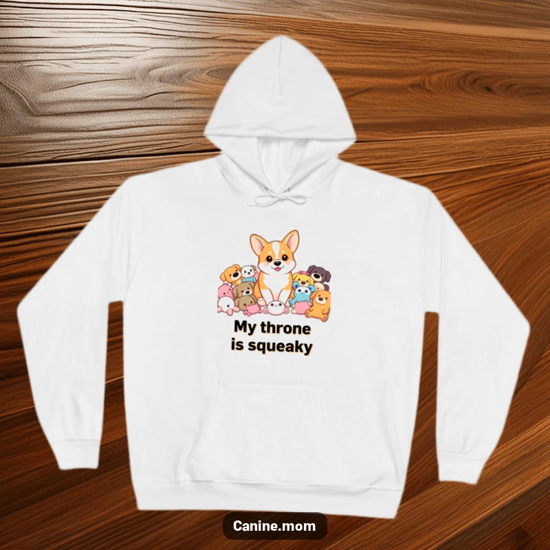 Funny Corgi Hoodie: A happy corgi sits amidst a heap of colorful dog toys, looking utterly pleased. A perfect funny gift.