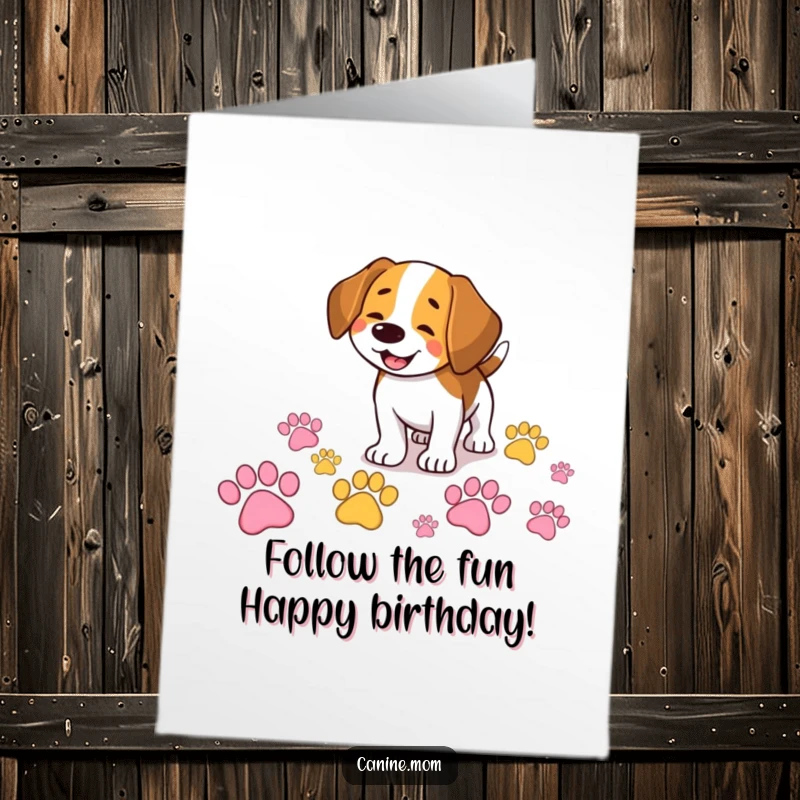 Funny Free Printable Birthday Card featuring a smiling beagle joyfully sniffing a trail of giant, colorful paw prints.